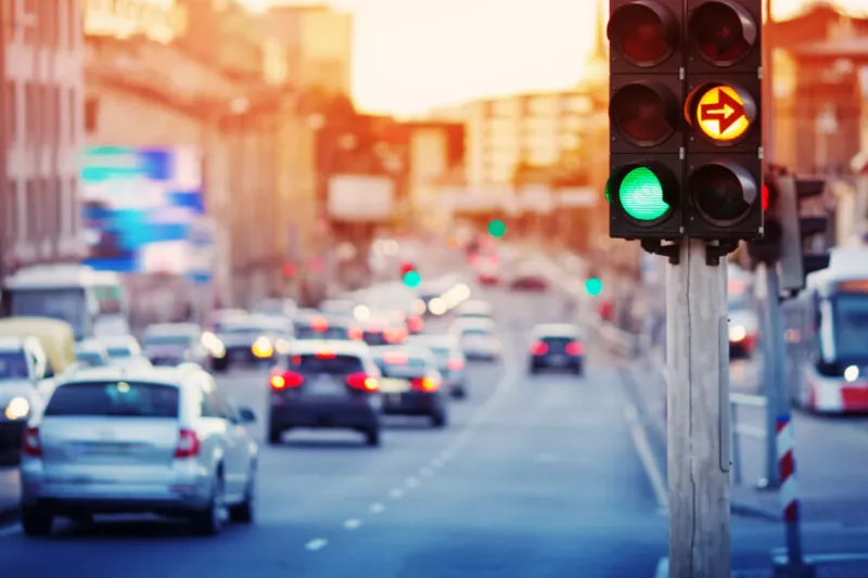 Smart city intersection with adaptive traffic lights and flowing vehicles at sunset, demonstrating Intelligent Transportation Systems (ITS) for efficient urban traffic management.
