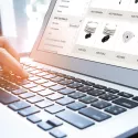 A hand using a laptop while the sun is shining on the hand