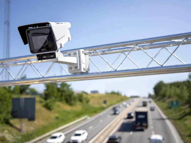 Axis intelligent traffic management camera monitoring vehicle flow on a highway for improved road safety and smart city efficiency.